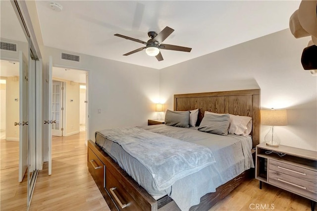 bedroom with light wood finished floors, visible vents, baseboards, and a ceiling fan