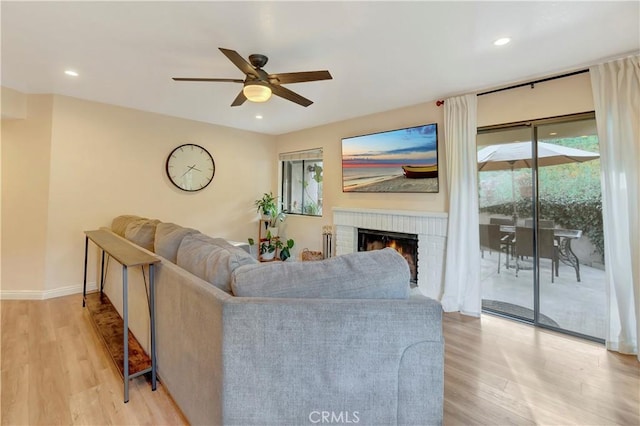 living room featuring recessed lighting, light wood-type flooring, and a fireplace