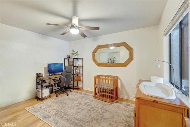 bedroom featuring a sink, light wood-style floors, and ceiling fan