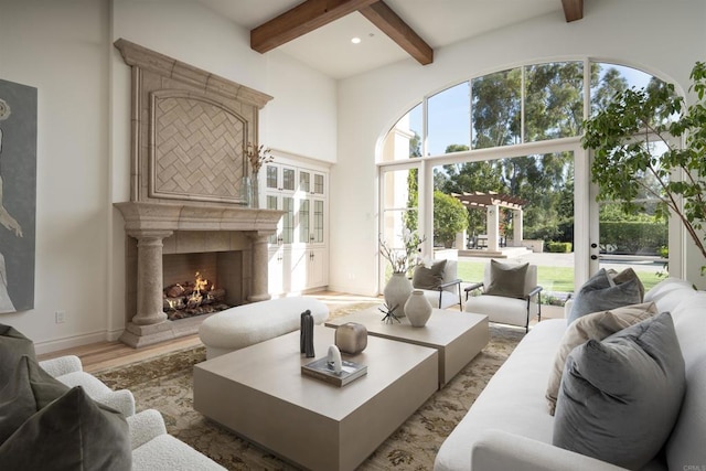 living room featuring beam ceiling, a tiled fireplace, and light hardwood / wood-style floors