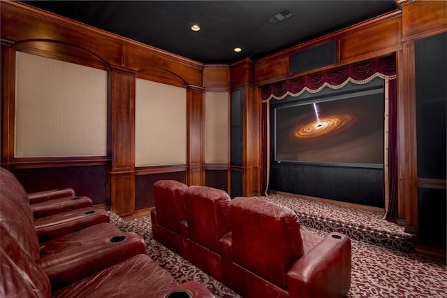 carpeted cinema featuring ornamental molding and wood walls