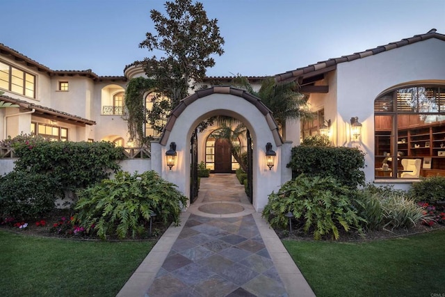 exterior entry at dusk featuring a lawn