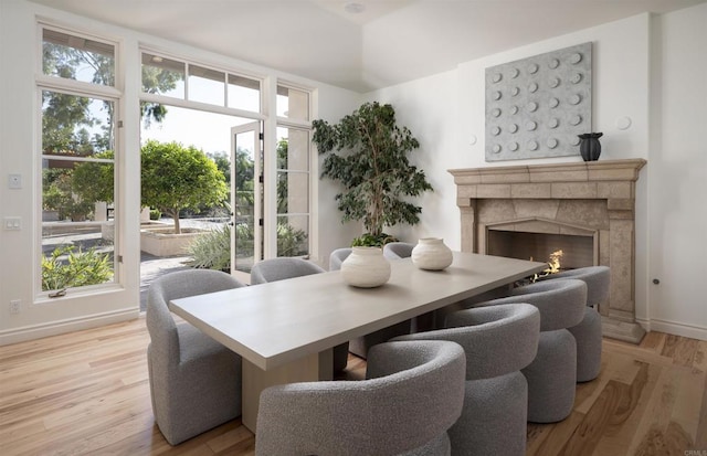 dining area with a stone fireplace and light hardwood / wood-style flooring