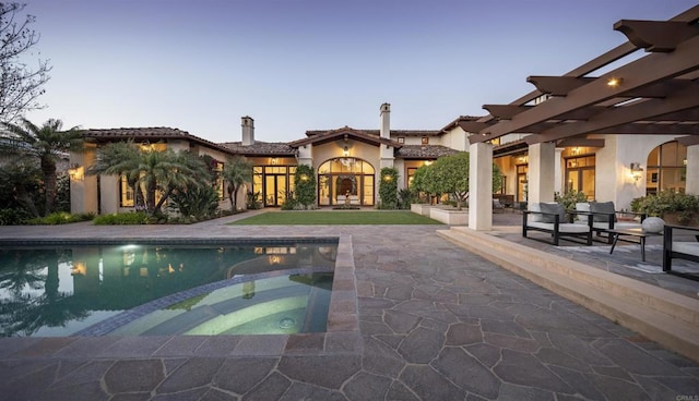 pool at dusk with an in ground hot tub, a pergola, and a patio area