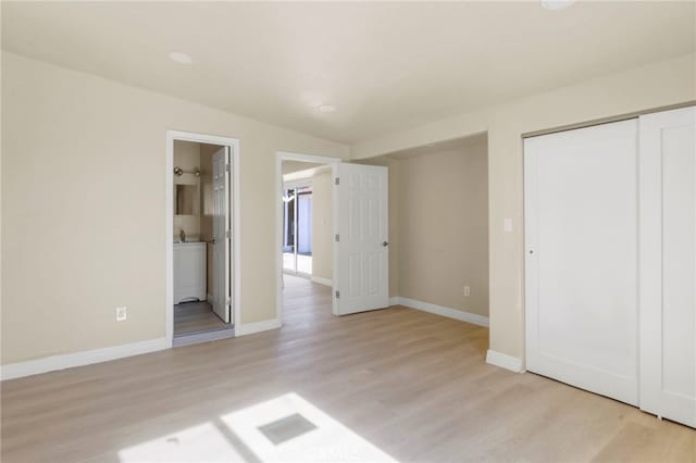 unfurnished bedroom featuring a closet, lofted ceiling, connected bathroom, and light hardwood / wood-style flooring