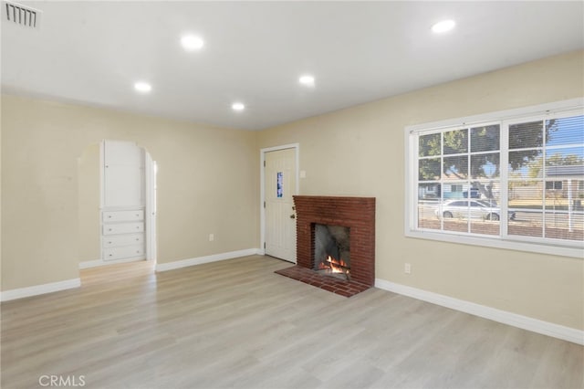 unfurnished living room featuring a fireplace and light hardwood / wood-style floors