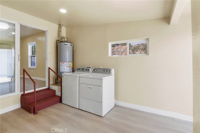 washroom with water heater, washer and dryer, and light hardwood / wood-style flooring