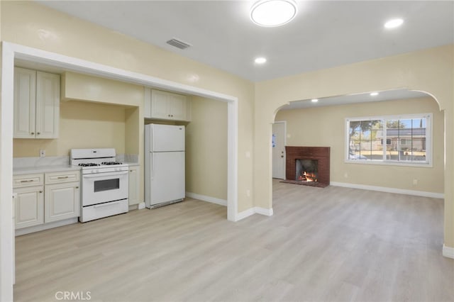 kitchen featuring a fireplace, white appliances, and light hardwood / wood-style flooring