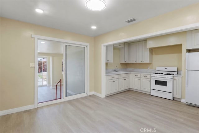 kitchen featuring white cabinetry, white appliances, sink, and light hardwood / wood-style flooring