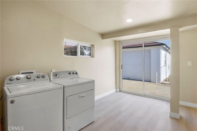 laundry area with washing machine and dryer and light wood-type flooring