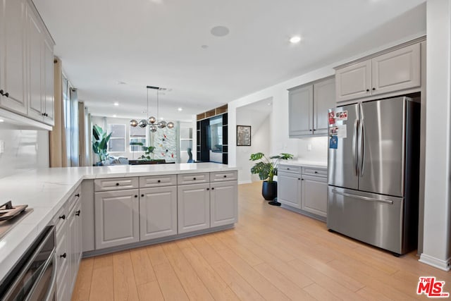 kitchen featuring light hardwood / wood-style flooring, gray cabinets, stainless steel appliances, and kitchen peninsula