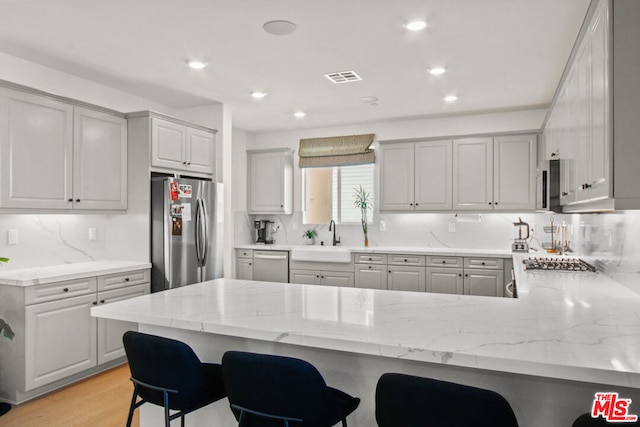 kitchen with stainless steel appliances, a kitchen bar, kitchen peninsula, and sink