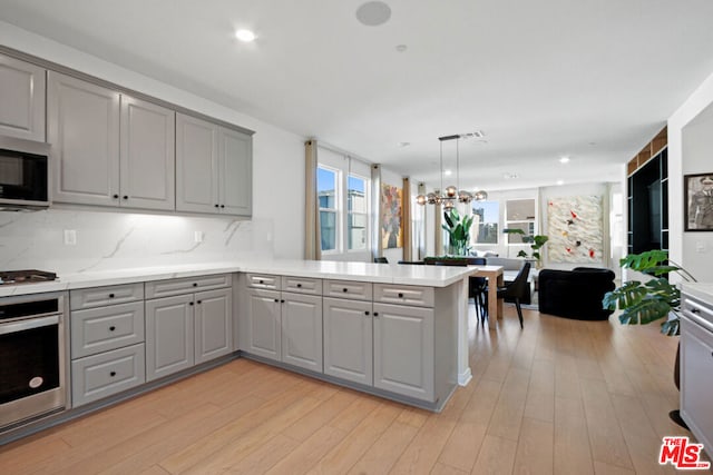 kitchen featuring stainless steel appliances, gray cabinets, and kitchen peninsula