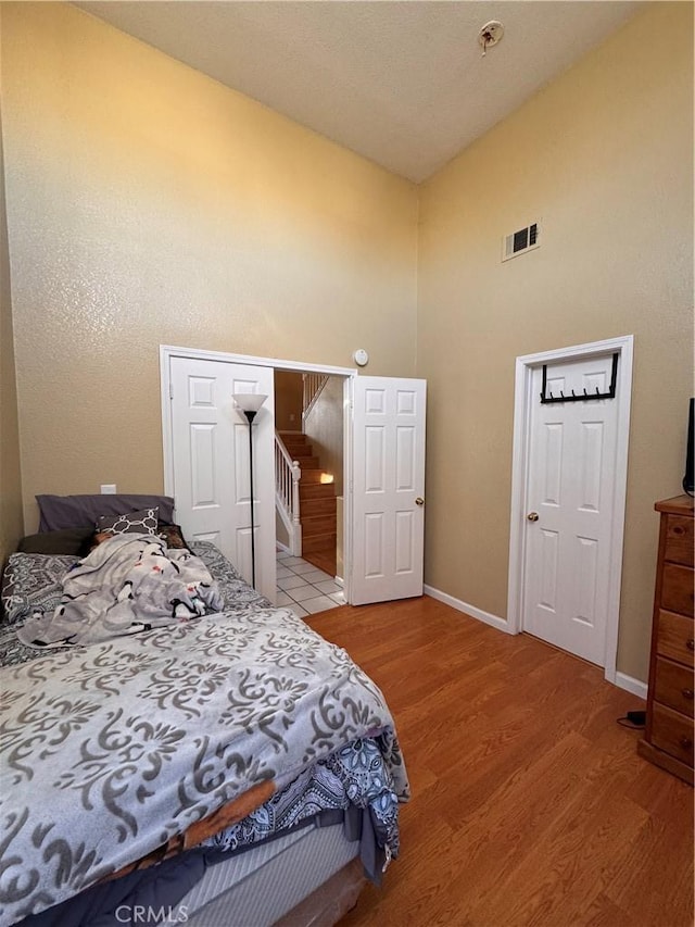 bedroom with wood-type flooring and high vaulted ceiling