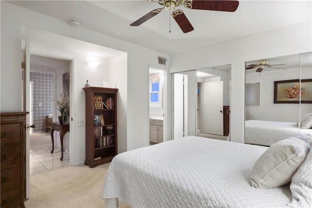 carpeted bedroom with ensuite bathroom and ceiling fan