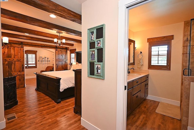 hallway with a barn door, dark hardwood / wood-style floors, beam ceiling, and a wealth of natural light