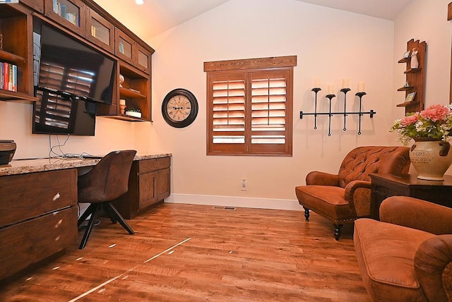 office with wood-type flooring, vaulted ceiling, and built in desk