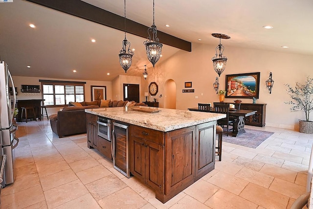 kitchen featuring wine cooler, decorative light fixtures, lofted ceiling with beams, stainless steel refrigerator, and a kitchen island