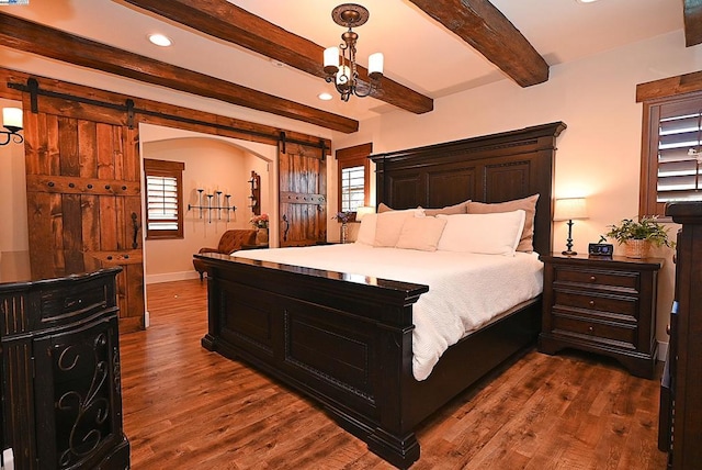 bedroom featuring dark hardwood / wood-style floors, a barn door, an inviting chandelier, and beam ceiling