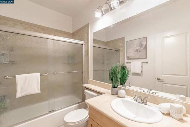 full bathroom featuring vanity, combined bath / shower with glass door, and toilet