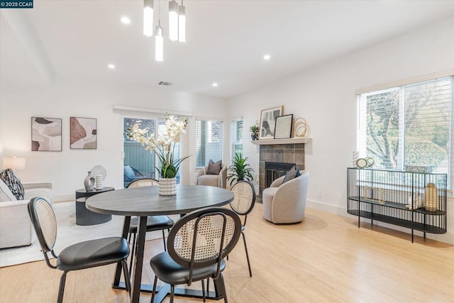 dining room with an inviting chandelier, a fireplace, and light hardwood / wood-style floors