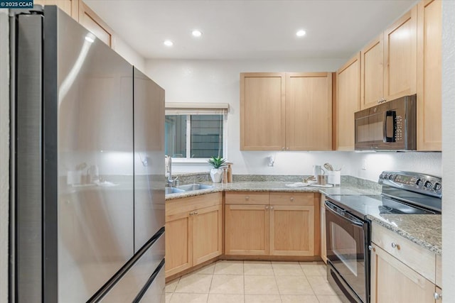 kitchen with light tile patterned floors, sink, black appliances, light stone countertops, and light brown cabinetry