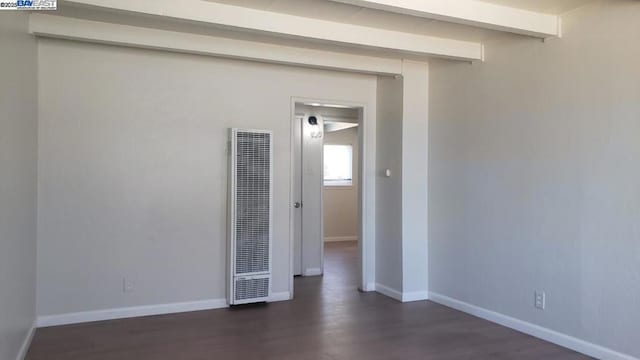 empty room featuring dark hardwood / wood-style flooring and beamed ceiling