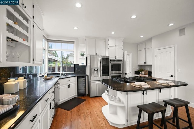 kitchen with wine cooler, white cabinetry, light wood-type flooring, appliances with stainless steel finishes, and a kitchen island