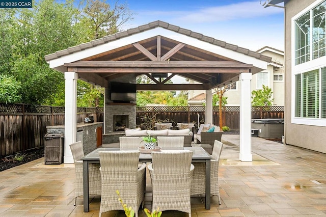 view of patio with a gazebo, a hot tub, and an outdoor living space with a fireplace