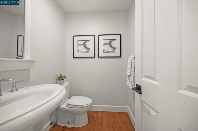 bathroom featuring sink, wood-type flooring, and toilet