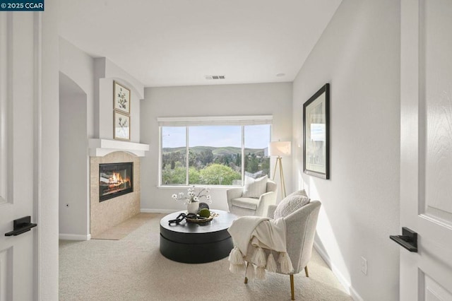 living room featuring a tile fireplace, a mountain view, and light carpet