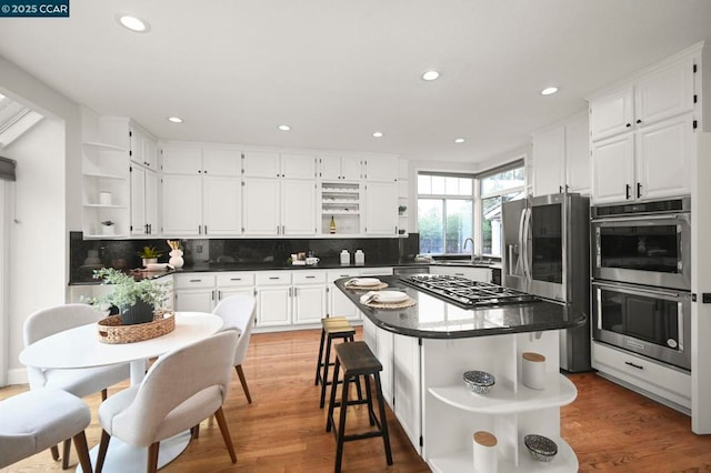 kitchen featuring white cabinetry, stainless steel appliances, a center island, and tasteful backsplash