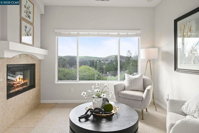 living area featuring plenty of natural light, a tiled fireplace, and a mountain view