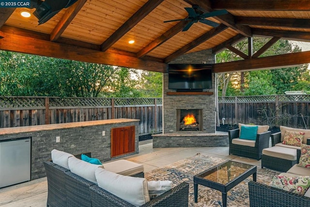 view of patio / terrace featuring a gazebo, an outdoor living space with a fireplace, and ceiling fan