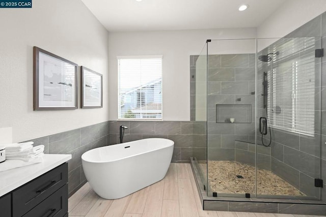 bathroom featuring independent shower and bath, vanity, hardwood / wood-style floors, and tile walls