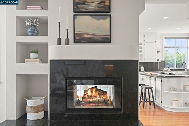 interior details with hardwood / wood-style flooring, a multi sided fireplace, decorative backsplash, and built in features