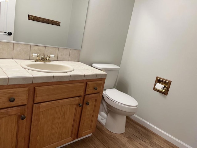 bathroom featuring tasteful backsplash, vanity, toilet, and hardwood / wood-style floors