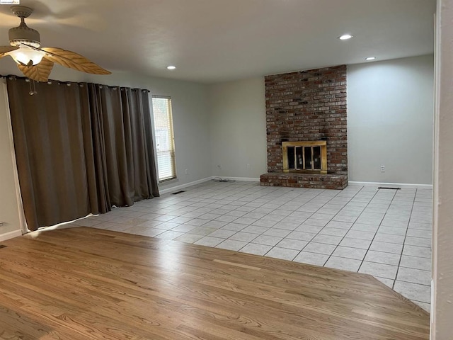 unfurnished living room featuring ceiling fan, light tile patterned floors, and a fireplace