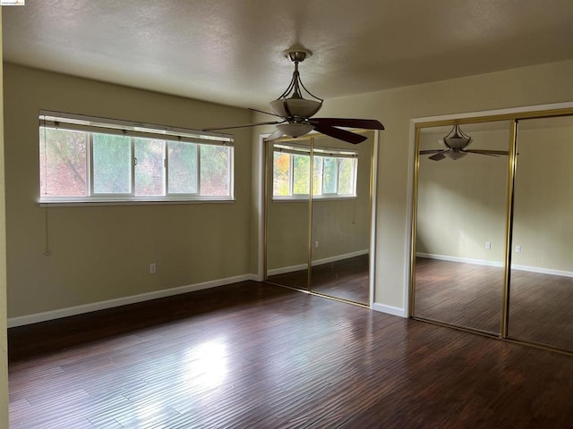 unfurnished bedroom featuring dark wood-type flooring and ceiling fan