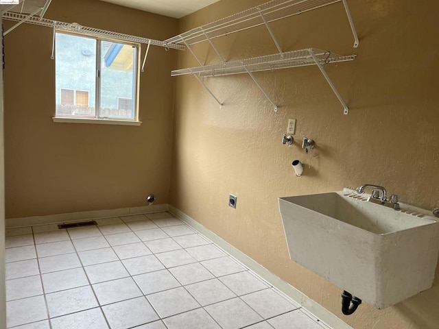 washroom with light tile patterned flooring, hookup for an electric dryer, and sink