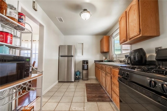 kitchen with light tile patterned floors, sink, and black appliances