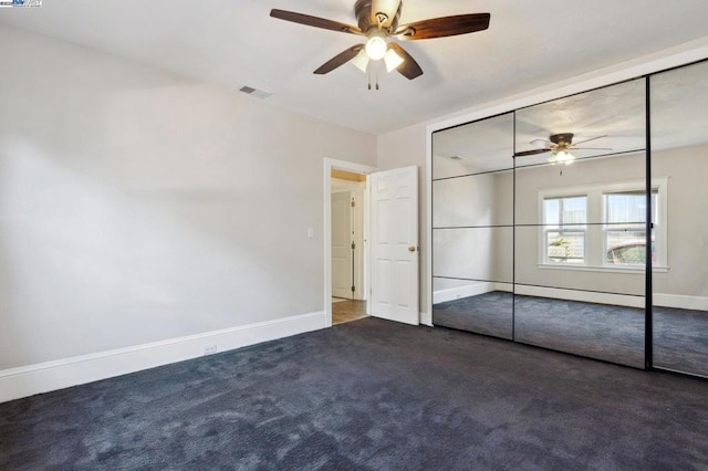 unfurnished bedroom featuring dark carpet, ceiling fan, and a closet