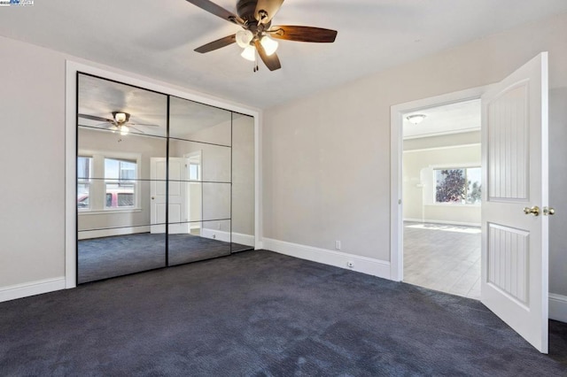 unfurnished bedroom with dark carpet and ceiling fan