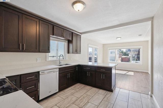 kitchen featuring dark brown cabinetry, dishwasher, sink, and kitchen peninsula