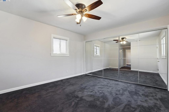 unfurnished bedroom with ceiling fan, a closet, and dark colored carpet