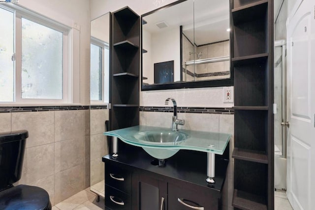 bathroom with tile patterned floors, vanity, combined bath / shower with glass door, and tile walls