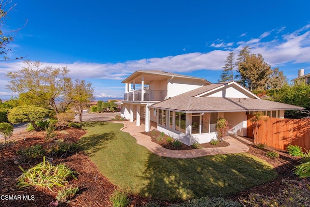 rear view of property with a yard, a sunroom, and a balcony