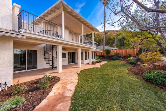 rear view of property with a lawn, a patio, and a balcony