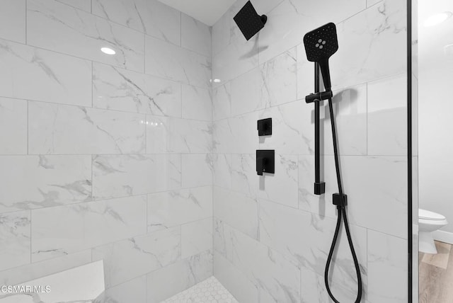 bathroom featuring a tile shower and toilet