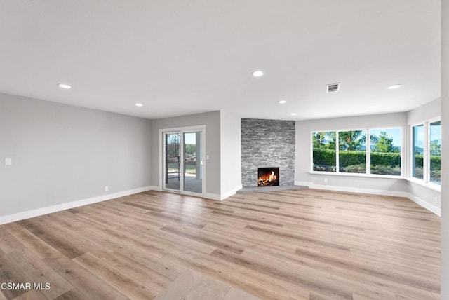 unfurnished living room featuring a wealth of natural light, a fireplace, and light hardwood / wood-style flooring